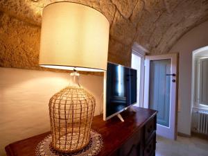 a lamp on a wooden table with a television and a lamp at Suite Sirene in Polignano a Mare