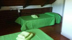 een kamer met 2 bedden met groene lakens en handdoeken bij La Fontana de Tandil in Tandil