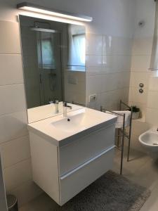 a white bathroom with a sink and a mirror at Apartman Blazek Kastav in Kastav