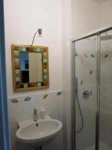 een badkamer met een wastafel en een douche met een spiegel bij lacasettabb in Massignano