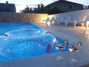 dois copos de vinho sentados numa mesa ao lado de uma piscina em Anna em Drage