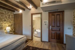 a bedroom with a bed and a bathroom with a tub at Hotel Arhontiko Vourloka in Pramanta