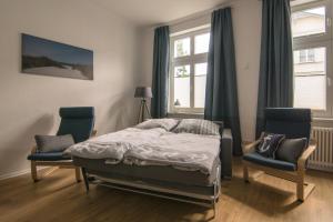a bedroom with a bed and two chairs and a window at Ferienwohnung Sundkieker in Stralsund