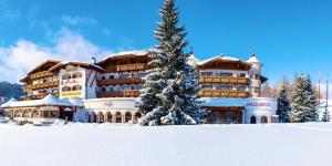 un grande edificio con un albero di Natale nella neve di Hotel Residenz Hochland a Seefeld in Tirol