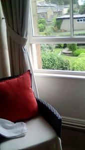 a red pillow sitting on a couch next to a window at Aydon House in Alnwick +9 photos