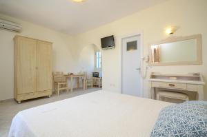 a white bedroom with a bed and a table at Orkos Blue Coast in Mikri Vigla
