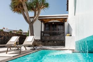 - une piscine avec 2 chaises longues à côté d'une maison dans l'établissement Drago by AGM Resorts, à Puerto del Carmen