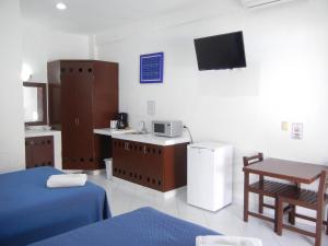 a room with two beds and a tv on the wall at Hotel Plaza Almendros in Isla Mujeres