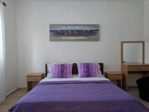 Beni Bungalows في أولتسينج: غرفة نوم مع سرير أرجواني مع وسائد أرجوانية