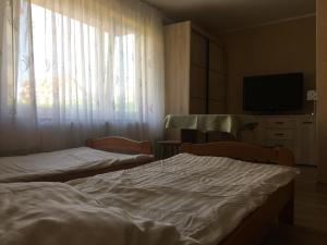 two beds in a room with a window and a tv at Anielskie Pokoje in Władysławowo