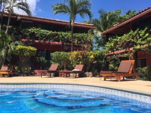 una piscina frente a una casa con palmeras en Massai Apartments, en Playa Flamingo