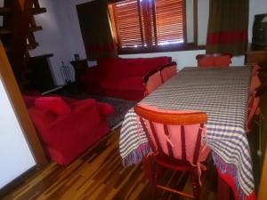 a dining room table with red chairs and a red couch at Apartamento no Centro de Campos do Jordao in Campos do Jordão