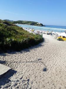 una playa de arena con sombrillas y gente en la playa en Apartamento em Cabo Frio, en Cabo Frío