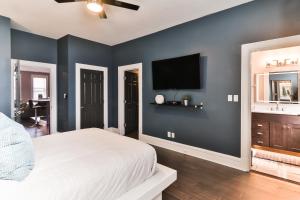 1 dormitorio con 1 cama y TV en la pared en Luxury Apt w/ Spectrum Mood Lighting - Historic Cherokee Street Antique Row en Maryland Heights