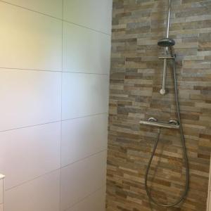 a shower in a bathroom with a brick wall at Bungalow Groen in Den Burg
