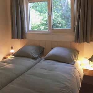 two beds in a bedroom with two windows at Bungalow Groen in Den Burg
