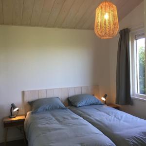 a bedroom with two beds and a chandelier at Bungalow Groen in Den Burg
