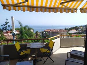 patio con mesa y sillas en el balcón en Nero Basalto Azzurro Mare, en Aci Castello