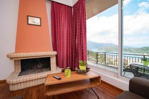 a living room with a fireplace and a large window at Calypso Apartments in Vathi