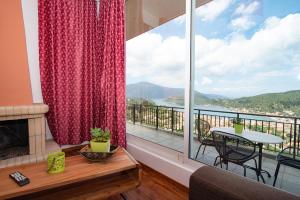 a living room with a fireplace and a large window at Calypso Apartments in Vathi