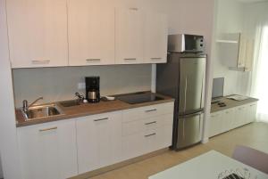 a kitchen with white cabinets and a stainless steel refrigerator at Condominio Shedir in Bibione