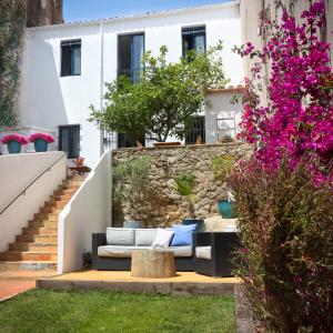 een tuin met een bank en paarse bloemen bij Hotel Casa Calella in Calella de Palafrugell