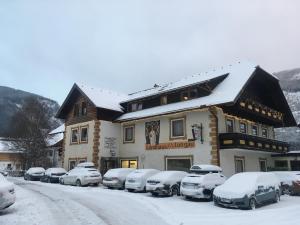 ein schneebedecktes Gebäude mit Autos auf einem Parkplatz in der Unterkunft Landhaus Lungau in Sankt Michael im Lungau