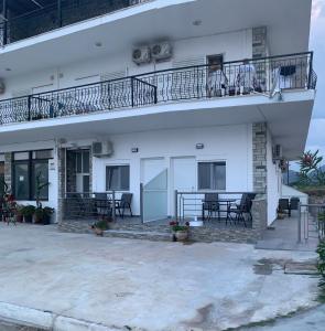 a white house with a balcony and tables and chairs at Skoulidis Family Apartments in Nea Vrasna