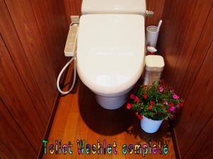 a bathroom with a toilet and two flowers in a room at Yakushima Cottage Kukai in Yakushima