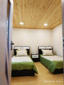 a bedroom with two beds and a wooden ceiling at Caspian Star in Sumqayıt