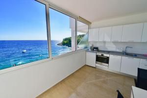 a kitchen with white cabinets and a view of the ocean at Apartments Petarcica Beach in Zavala