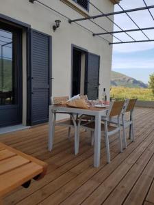 einen weißen Tisch und Stühle auf einer Holzterrasse in der Unterkunft Entre mer et montagne, en plein maquis in Vallecalle