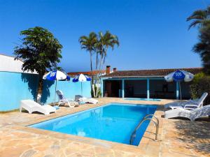 a pool with chairs and umbrellas next to a house at Associação Sabesp Ilha Comprida in Ilha Comprida