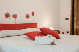 a bed with red pillows and a towel and flowers on it at Pretty House Sorrento in Piano di Sorrento