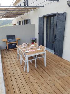 una mesa blanca y sillas en una terraza de madera en En plein maquis,entre mer&montagne en Vallecalle