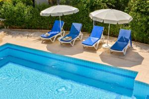 a group of chairs and umbrellas next to a pool at Kilic- 5 Bedroom Holiday Villa in Hisaronu in Ovacik