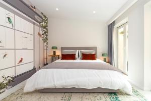 a white bedroom with a large bed with red pillows at Bela Vista Palace Apartments in Cascais