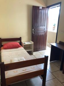 ein Schlafzimmer mit einem Bett, einem Schreibtisch und einer Tür in der Unterkunft Capivari Centro Hotel in Capivari
