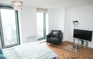 a bedroom with a bed and a chair and a television at Studio Apartments Free street parking subject to availability in Manchester