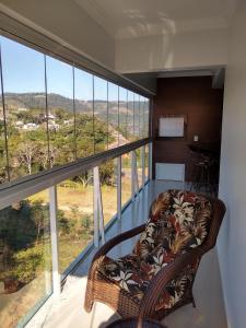 a room with a chair in front of a large window at Apartamento NOVO temporada in Piratuba
