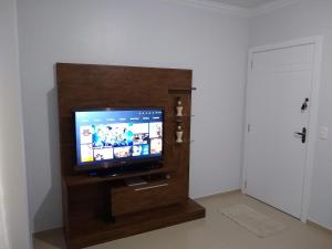 een flatscreen-tv in een houten entertainmentcentrum bij Apartamento NOVO temporada in Piratuba
