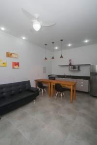 sala de estar con sofá negro y mesa en Flat com serviços na Riviera, en Bertioga