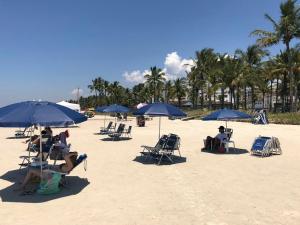 Flat com serviços na Riviera في بيرتيوغا: مجموعة من الناس جالسين على شاطئ فيه مظلات