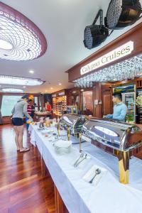 una línea de buffet en un crucero con personas preparando comida en Calypso Cruises, en Ha Long