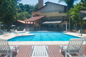 een zwembad met twee stoelen en een huis bij Flat com serviços na Riviera in Bertioga