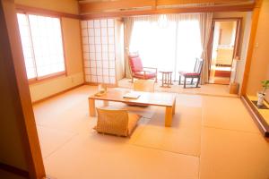 uma sala de estar com uma mesa, cadeiras e janelas em Yugawara Retreat Goen no Mori em Yugawara