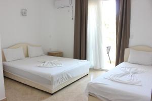 a bedroom with two beds with white sheets and a window at Presheva Rooms in Ulcinj