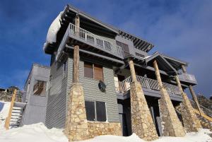 a large house with snow on the ground at Ultima Apartments in Mount Hotham