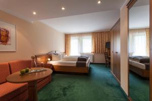 ein Hotelzimmer mit einem Bett und einem Sofa in der Unterkunft Natur Residenz Anger Alm - Adults only in Sankt Leonhard im Pitztal