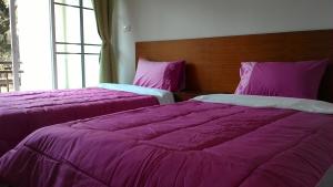 2 camas en una habitación con mantas moradas en M.place Maerim en Chiang Mai